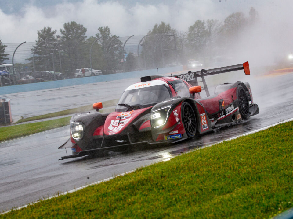 A race car is driving down the track in the rain.