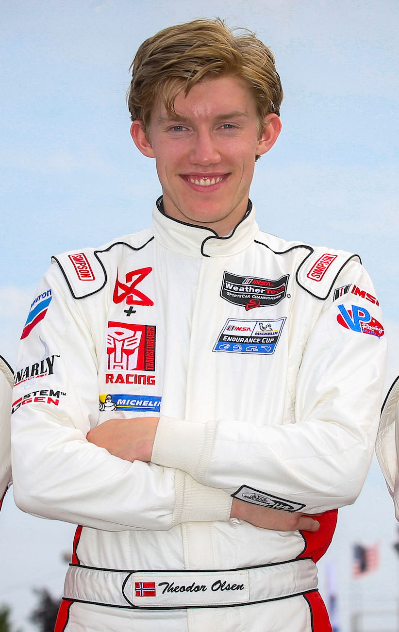 A man in white racing suit standing with his arms crossed.